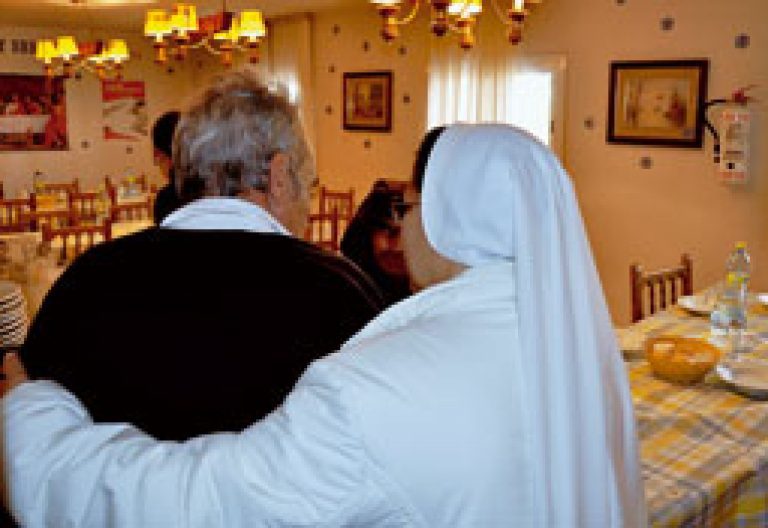 religiosa ayuda a un anciano en un centro de Cáritas