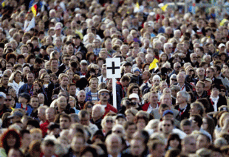 multitud de gente con un cartel con una cruz