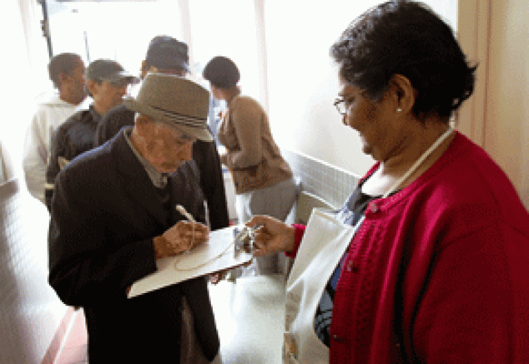 gente personas se apuntan en una lista para entrar en un comedor de Cáritas