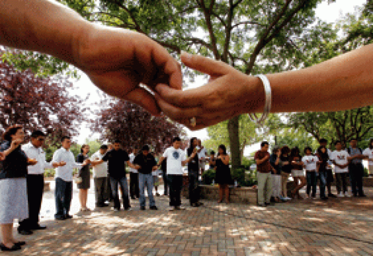 grupo de personas hacen un corro y se cogen de la mano