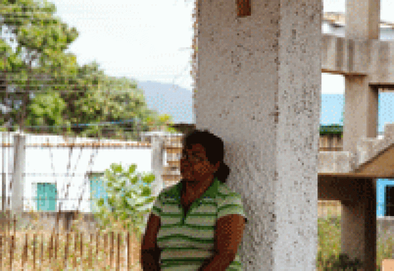 mujer en Venezuela sentada en un banco debajo de un crucifijo