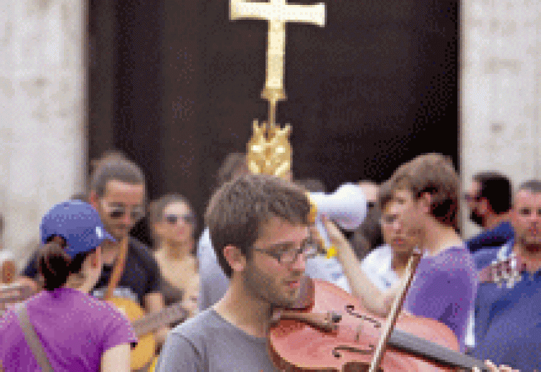 joven católico tocando el violín delante de un crucifijo