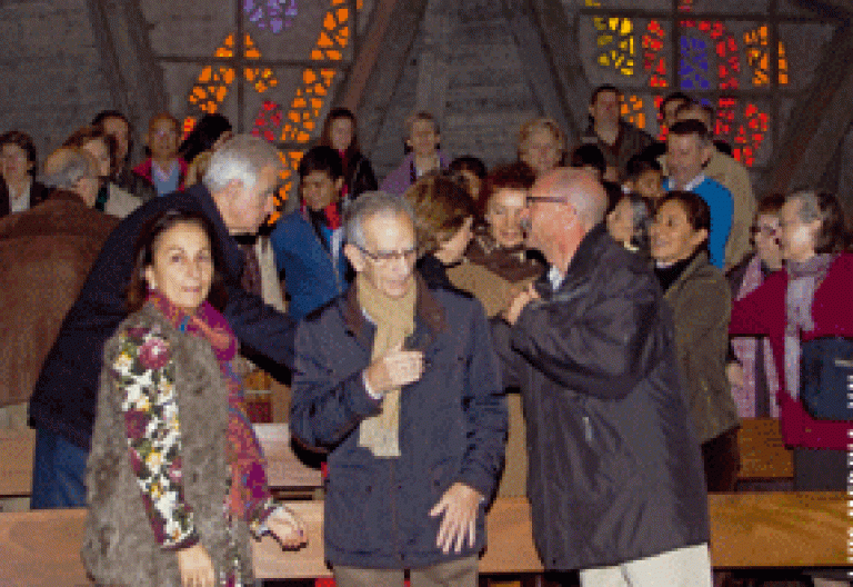 grupo de gente en el momento de la paz durante la celebración de la misa