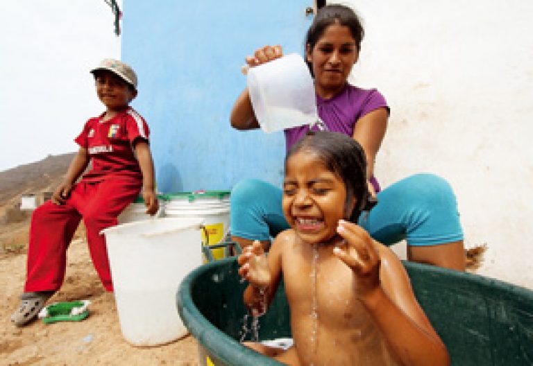 mujer madre bañando a niños en Perú