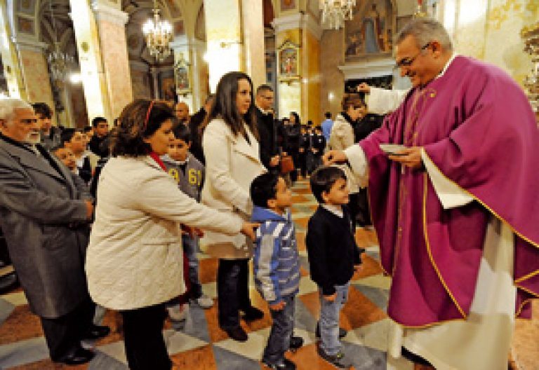 párroco durante la imposición de la ceniza a niños y fieles