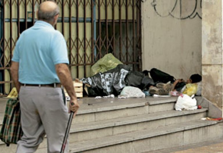 niño joven sin techo durmiendo en la calle entre cartones