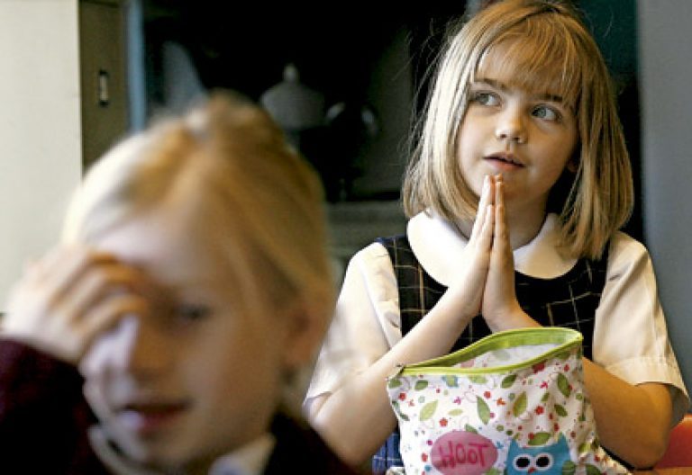 dos niñas rezando en clase de religión en la escuela