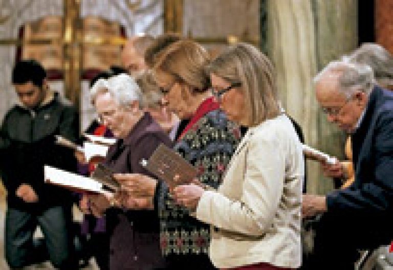 personas en una celebración rezan de rodillas