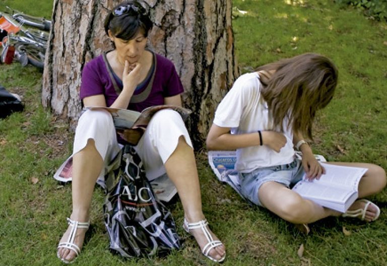 mujer y chica joven leyendo libros al aire libre en el parque