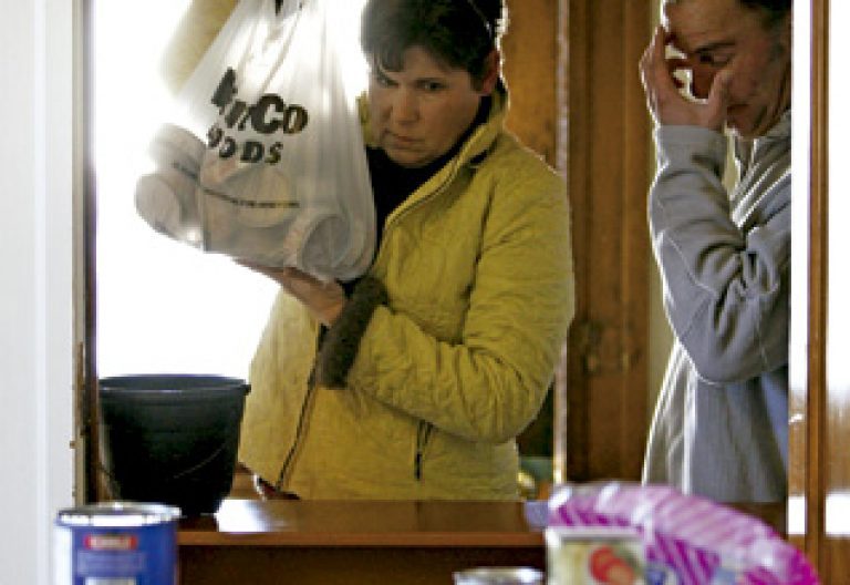 mujer recoge una bolsa de comida en un centro de Cáritas