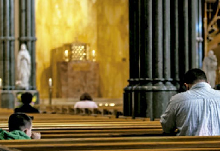 padre e hijo rezando en los bancos de una iglesia vacía