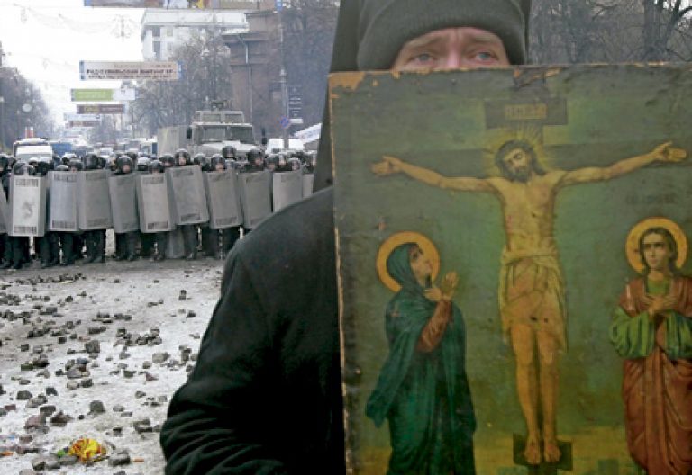 sacerdote cristiano mediando entre la policía y los manifestantes en Ucrania