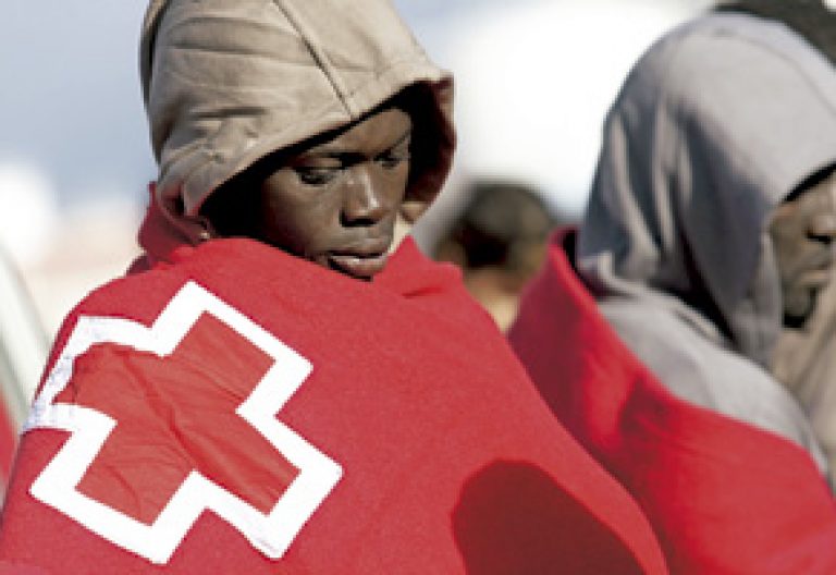 inmigrante africano con una manta de Cruz Roja