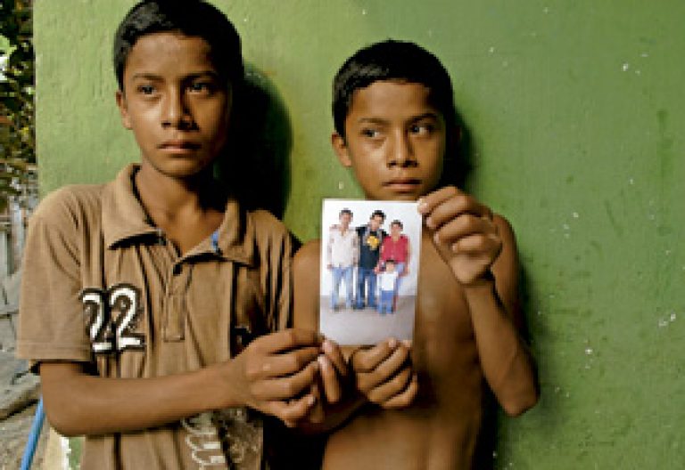 dos niños enseñan la foto de sus padres asesinados en Guatemala