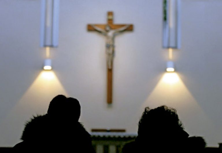 dos personas en una iglesia a contraluz contemplando un crucifijo