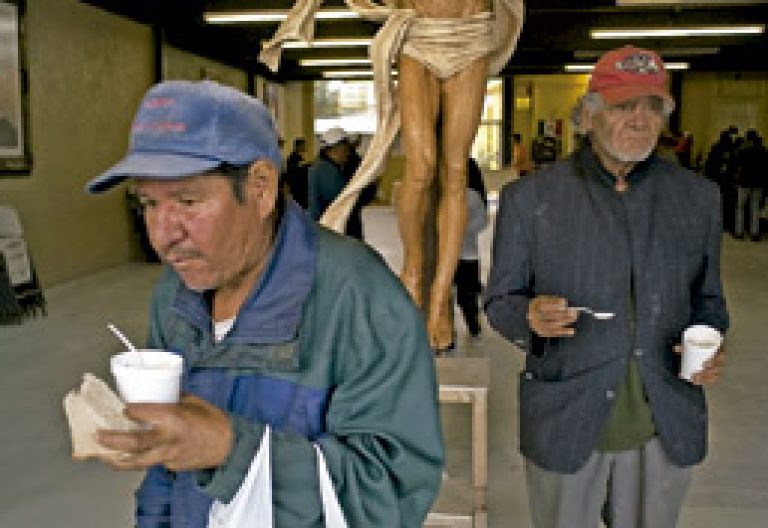 pobres salen de un comedor social junto a un crucifijo