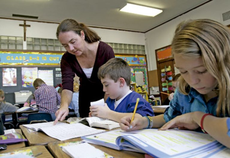 profesora con niños pequeños haciendo los deberes en un colegio católico