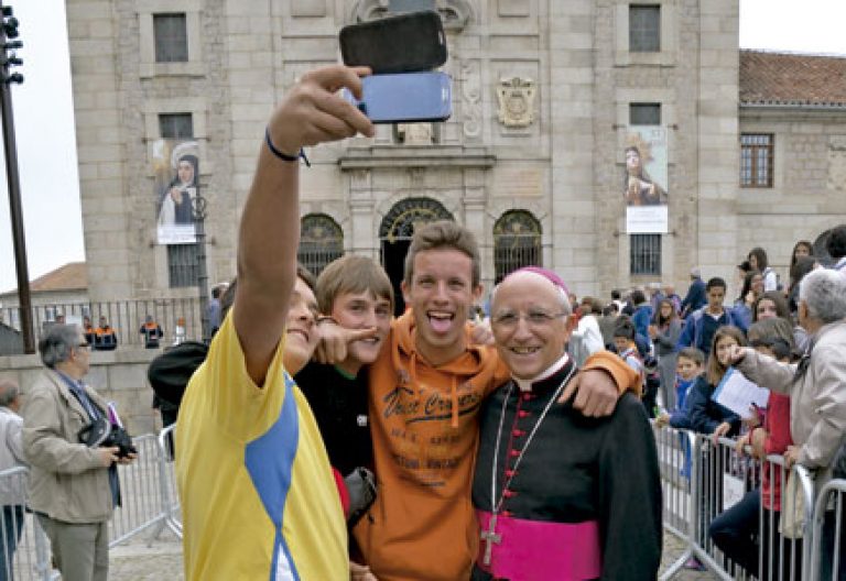 dos jóvenes se hacen un selfie con el obispo de Ávila, Jesús García Burillo