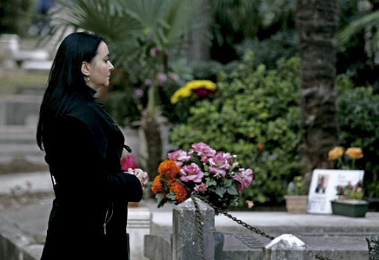 madre en el cementerio delante de una tumba