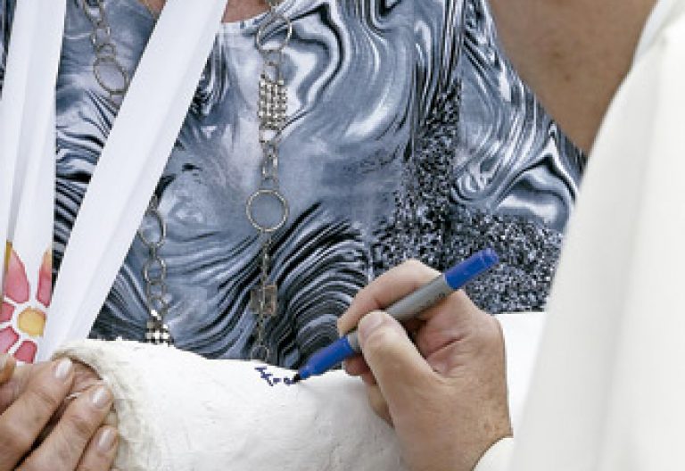 papa Francisco firma la escayola en un brazo a una mujer