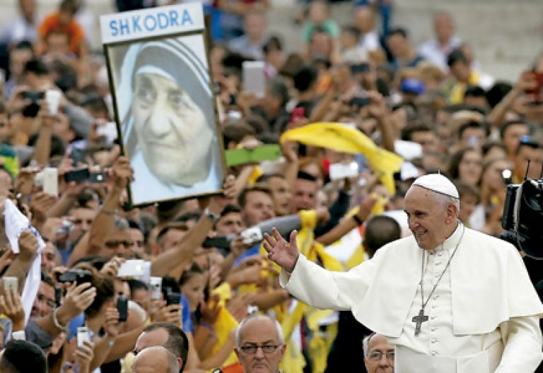 papa Francisco durante su viaje a Albania mientras la gente sostiene un cartel con la imagen de