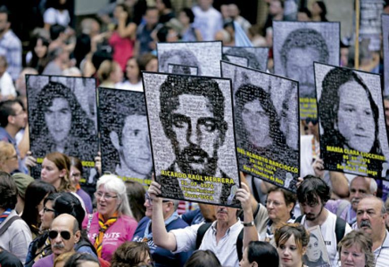 marcha ciudadana en Argentina con carteles con fotos de personas desaparecidas durante la dictadura