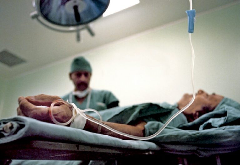médico atiende a un paciente en la cama de un hospital que está recibiendo una transfusión de sangre