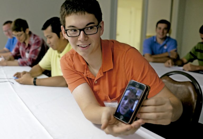 varios seminaristas jóvenes en clase con un teléfono móvil