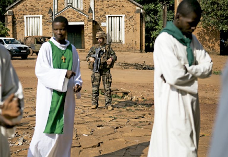 sacerdotes y soldado francés junto a una catedral en República Centrofricana