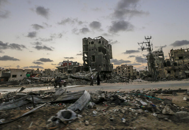 Los palestinos desplazados internos caminan cerca de edificios destruidos en Khan Yunis, al sur de